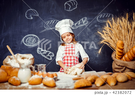 Adorable little girl in chef hat making dough 42382072