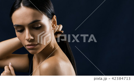 Side view of young woman holding her black hair Side view of young woman holding her black hair 42384713