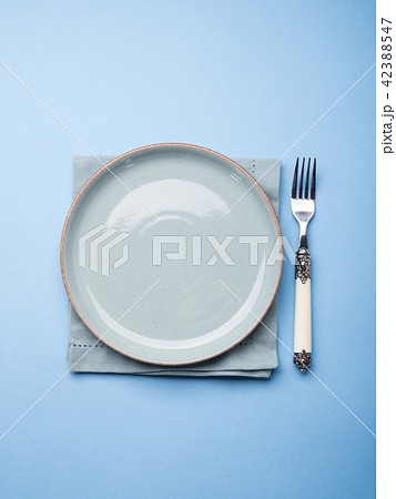 Blue pastel ceramic dish on napkin with fork Blue pastel ceramic dish on napkin with fork 42388547