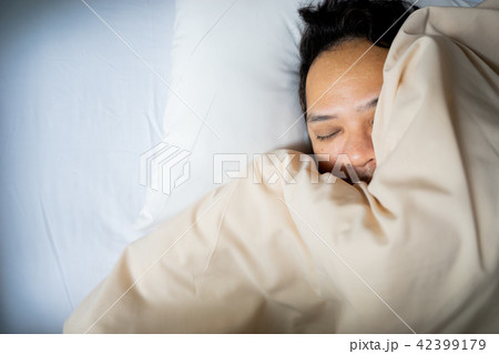 an Asian man face sleeping on white bed, top view an Asian man face sleeping on white bed, top view 42399179