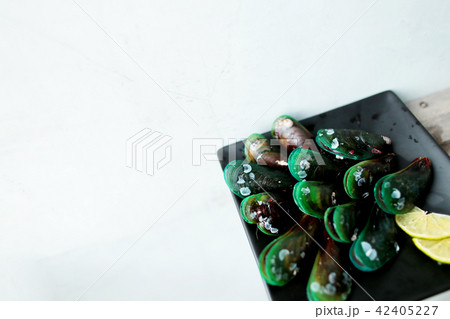 Black tasty mussels on dark square plate with lime in white background. Black tasty mussels on dark square plate with lime in white background. 42405227