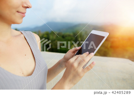 Suny photo portrait of young blonde woman using smartwatch, mountains in background, Bali. Suny photo portrait of young blonde woman using smartwatch, mountains in background, Bali. 42405289