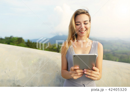 Young blonde woman using tablet with mountains background, Thailand. 42405320
