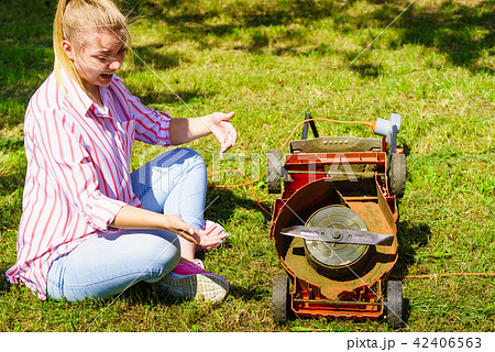 Female gardener with broken lawnmower Female gardener with broken lawnmower 42406563