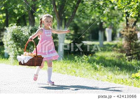 girl runs along the road with a basket of bread. girl runs along the road with a basket of bread. 42413066