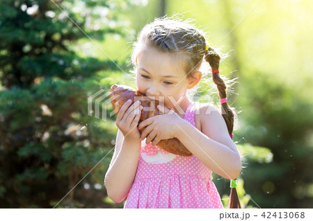 A child bites bread in nature. 42413068