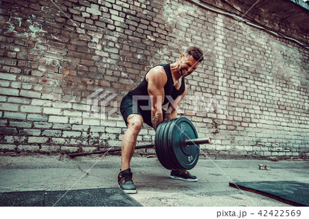 Athletic man working out with a barbell. Strength and motivation. Exercise for the muscles of the Athletic man working out with a barbell. Strength and motivation. Exercise for the muscles of the 42422569