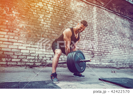 Athletic man working out with a barbell. Strength and motivation. Exercise for the muscles of the 42422570