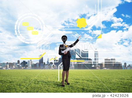 Camera headed woman standing on green grass against modern cityscape 42423026