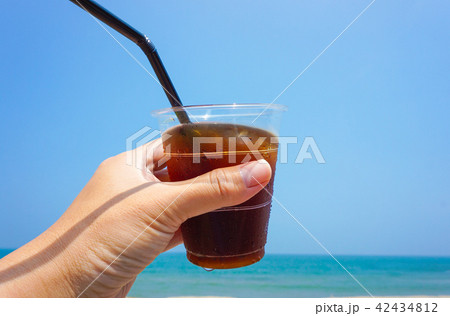 ビーチでアイスコーヒーを飲む 42434812