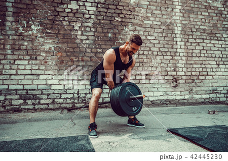 Athletic man working out with a barbell. Strength and motivation. Exercise for the muscles of the 42445230