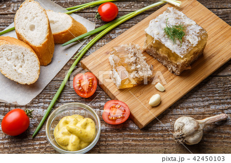 Homemade jelly meat with mustard, bread, tomatoes and garlic on the table. Holodets 42450103