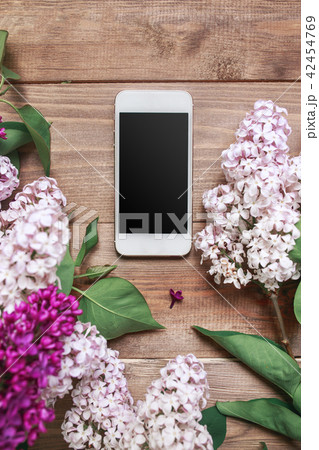 Bouquet of lilac flowers on wooden planks with mobile phone. 42454769