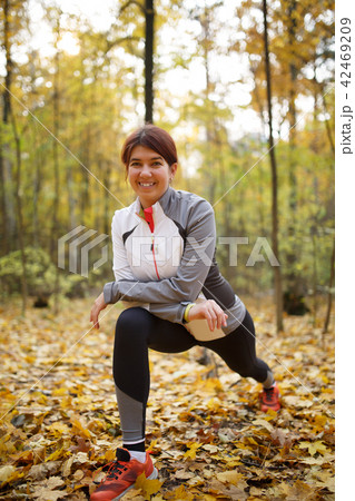 Autumn photo of sporty woman stretching in forest at morning against background of trees Autumn photo of sporty woman stretching in forest at morning against background of trees 42469209