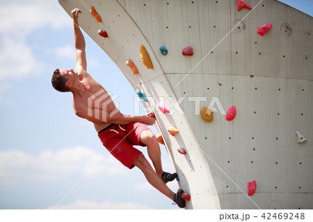 Photo of sportive guy exercising on wall for climbing against cloudy sky Photo of sportive guy exercising on wall for climbing against cloudy sky 42469248