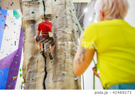 Photo of sporty man on climbing wall and female trainer Photo of sporty man on climbing wall and female trainer 42469273