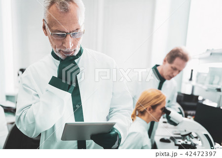 Chemist wearing glasses feeling thoughtful at work Chemist wearing glasses feeling thoughtful at work 42472397