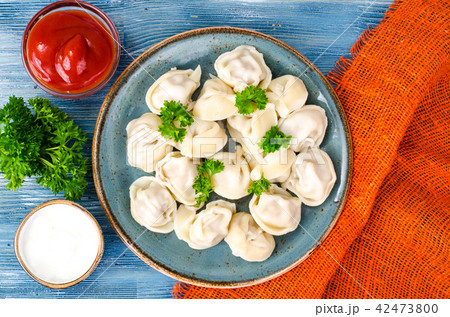Tasty homemade meat dumplings of wholemeal flour, sprinkled with fresh parsley in plate on wooden 42473800