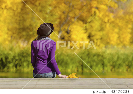 Girl in a hat sits on the dock and admires colors 42476283