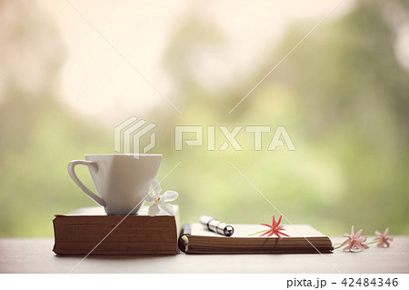 White cup and notebooks white flowers at windows White cup and notebooks white flowers at windows 42484346
