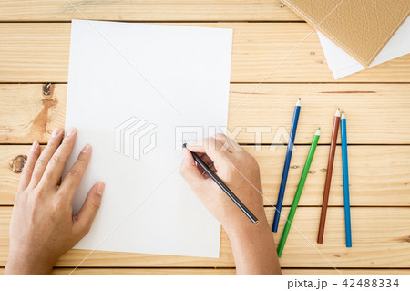 Hands drawing on paper on wooden table background Hands drawing on paper on wooden table background 42488334