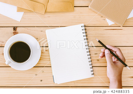 Hands writing on wooden table with office supplies Hands writing on wooden table with office supplies 42488335