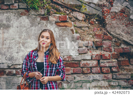 Beautiful girl is standing against brick wall 42492073