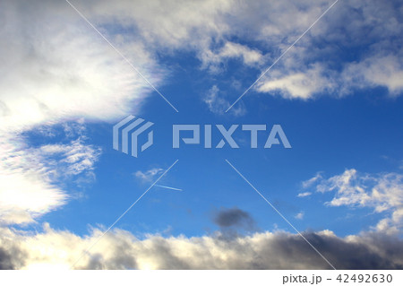 blue sky with clouds and a condensation trail 42492630