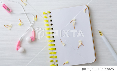 Earphones and notebook with flower on white table 42499025