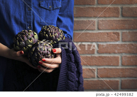 Artichokes are fresh in the hands of women. Bouquet from vegetables. Healthy Italian food. 42499382