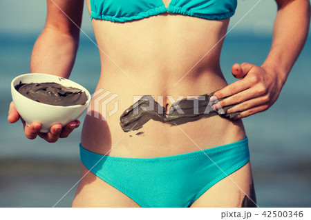 Woman smearing mud mask on the body on the beach Woman smearing mud mask on the body on the beach 42500346