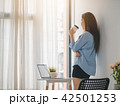 Beautiful young asian girl standing beside windows 42501253