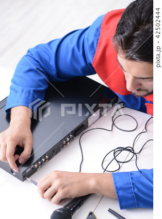 Man repairman repairing dvd player at service center Man repairman repairing dvd player at service center 42502444