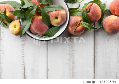 Fresh peaches fruits with leaves on wooden background Fresh peaches fruits with leaves on wooden background 42502594