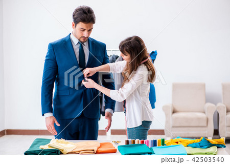 Professional tailor taking measurements for formal suit Professional tailor taking measurements for formal suit 42503540