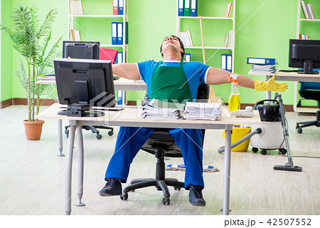 Handsome man cleaning office with vacuum cleaner 42507552