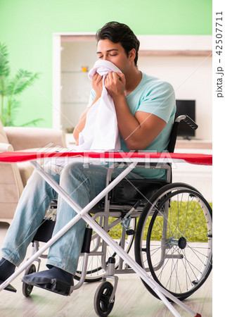 Disabled man on wheelchair ironing clothing 42507711