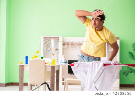 Leg injured man doing clothing ironing at home Leg injured man doing clothing ironing at home 42508256