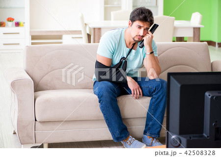 Arm injured man sitting on the sofa watching tv Arm injured man sitting on the sofa watching tv 42508328