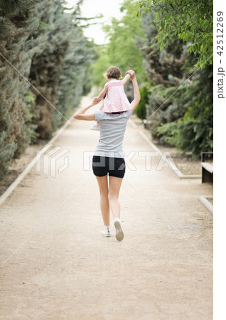 Little girl walking on the shoulders of her mother 42512269