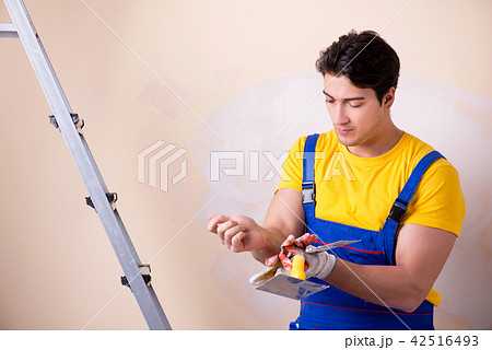 Young contractor employee applying plaster on wall Young contractor employee applying plaster on wall 42516493