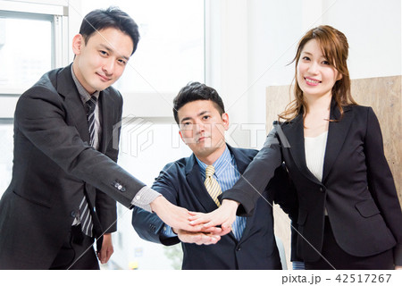 中央で手を合わせる3人のビジネスピープルの写真素材
