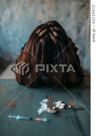 Junkie sitting at the table with drugs and syringe Junkie sitting at the table with drugs and syringe 42519472