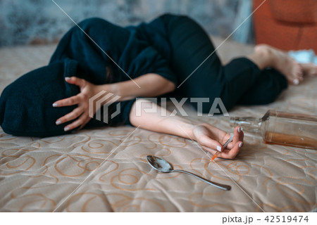 Female druggy with syringe in hand lies in bed Female druggy with syringe in hand lies in bed 42519474