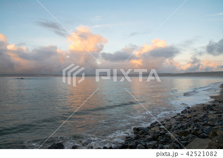 朝日に照らされて赤くなる雲と砂と岩の混ざった海岸　イギリスコーンウォールの海岸にて 42521082