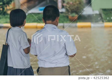 Boy and girl wait to cross flooded street Boy and girl wait to cross flooded street 42525362