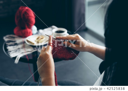Close up shot of young woman hands knitting a red scarf handicra Close up shot of young woman hands knitting a red scarf handicra 42525838