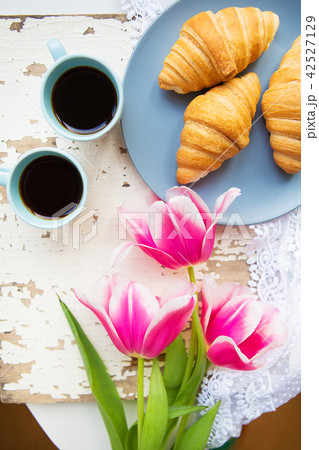 coffee, croissants and three beautiful pink tulips on old white table coffee, croissants and three beautiful pink tulips on old white table 42527129