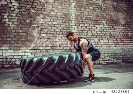 Muscular fitness man moving large tire. Muscular fitness man moving large tire. 42528361