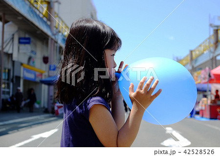 風船を膨らませる女の子の写真素材